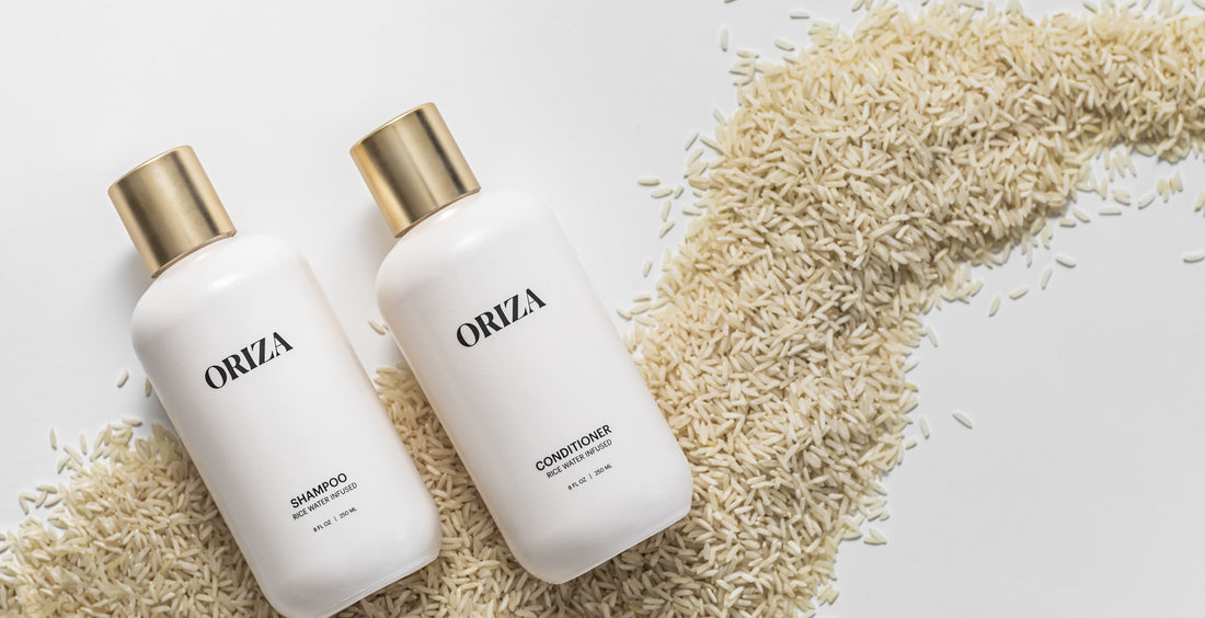 Oriza rice water shampoo and conditioner beside a sweep of uncooked rice