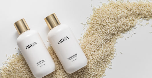 Oriza rice water shampoo and conditioner beside a sweep of uncooked rice