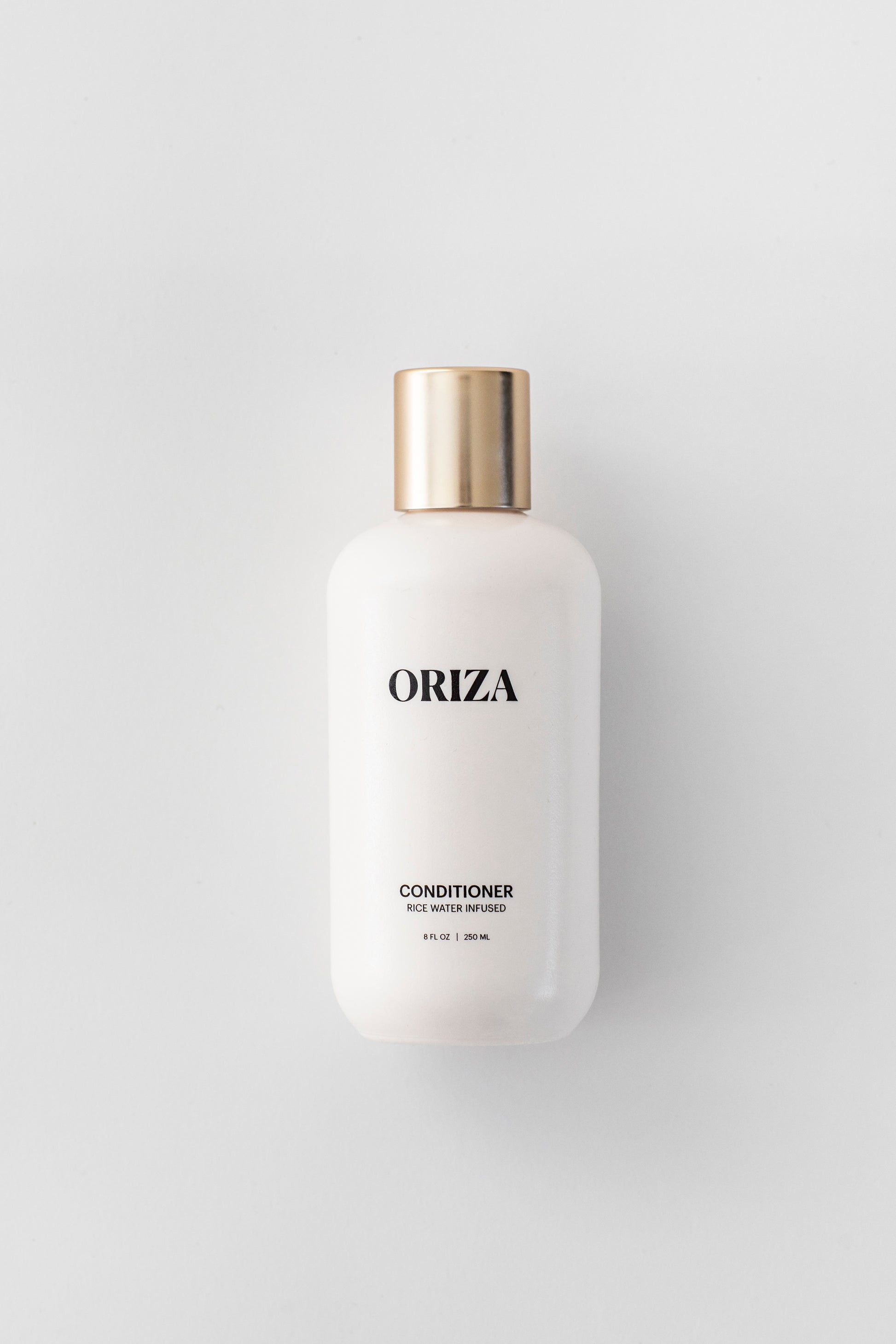 Oriza rice water infused conditioner in a sleek white bottle with a gold cap on a clean white background.